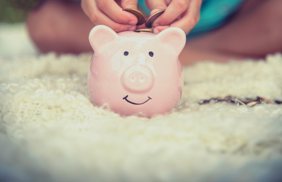 Child putting money in a piggy bank