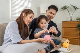 Parents with young child adding money to piggy bank