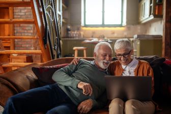 Man and woman on couch looking at a laptop