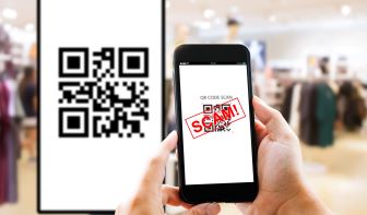 Person holding a phone with a QR Code and the word Scam